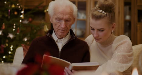 granddaughter and grandfather looking at photo album in house