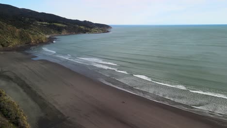 Cinematic-flight-over-Raglan-black-sand-beach-along-New-Zealand's-West-coast