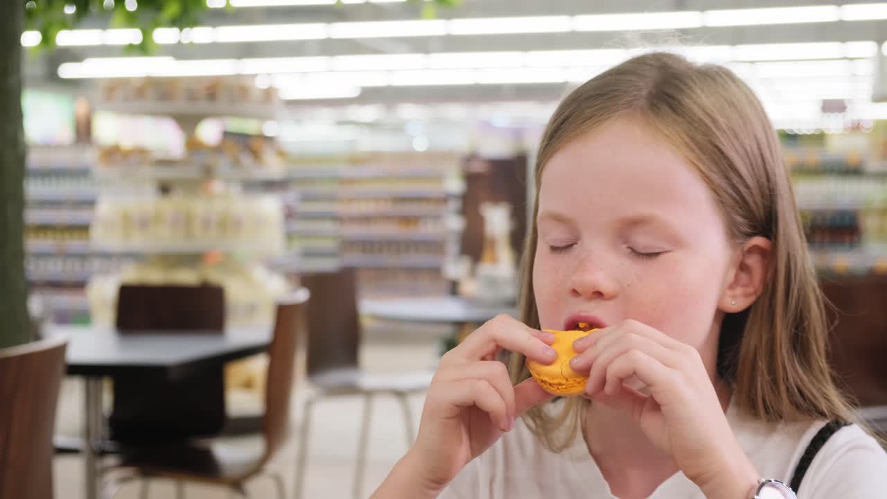 Girl Eating a Macaron in a Supermarket Cafe