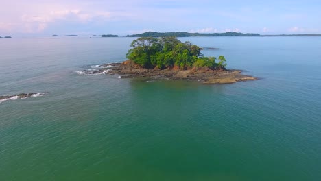 s'approchant lentement d'une petite île de baron couverte d'un terrain rocheux et d'une petit forêt d'arbres près de boca chica, au panama