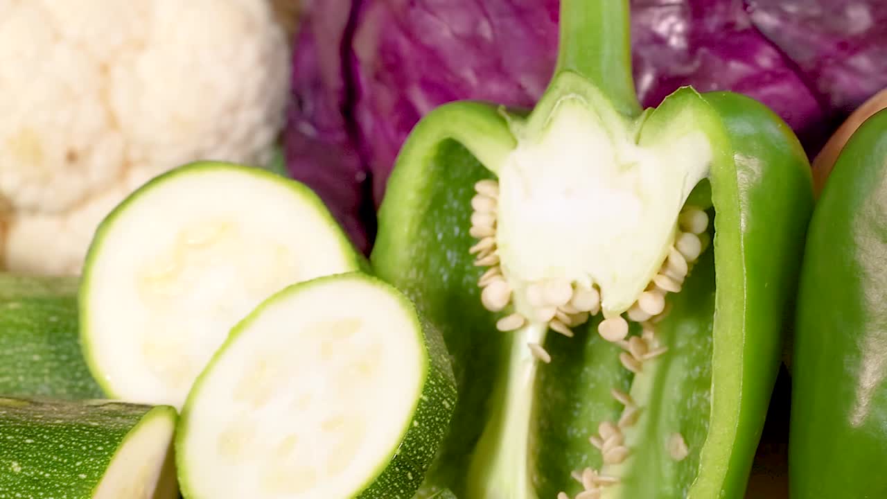 A close-up view of colorful vegetables including zucchini, radishes, tomatoes, carrots, and peppers, highlighting their textures and freshness.