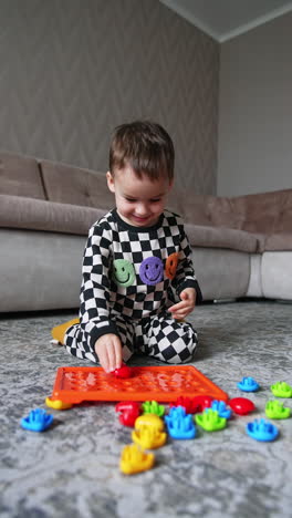 adorable happy baby boy sits on the floor near his toys. low angle view on the toddler playing a game at home.