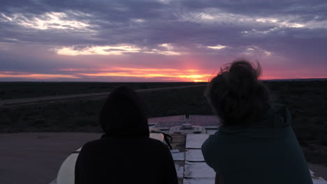 silhouette of two peoples sitting on bus and enjoying amazing sunset view in background,ascend shot