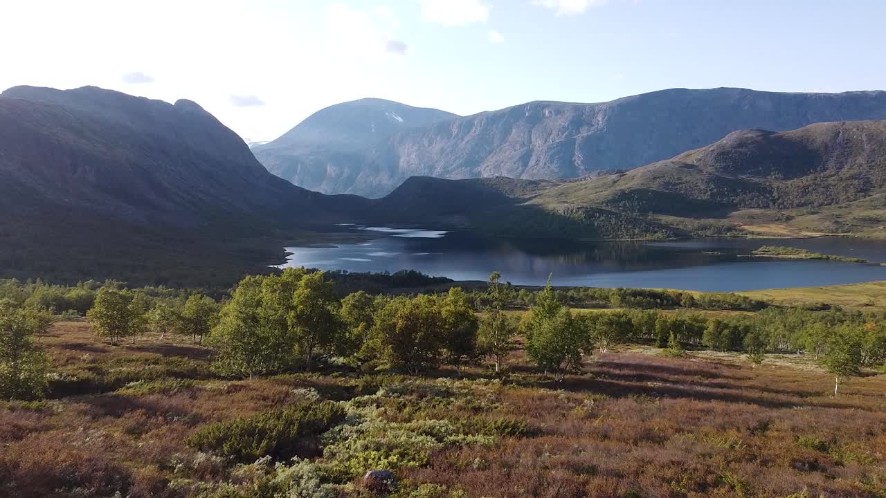 Nyt et fugleperspektiv over Jotunheimen nasjonalpark, hvor dramatiske fjellandskap, rolige innsjøer og frodige daler utfolder seg i et fantastisk skue