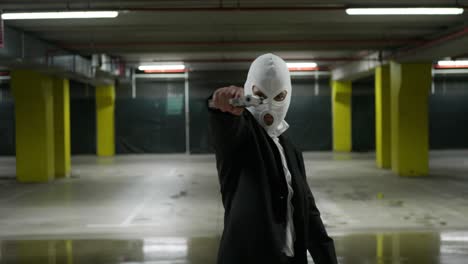 man in a suite with a white mask turning and pointing a gun criminal