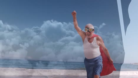 animation of clouds over senior caucasian man wearing superhero costume on beach