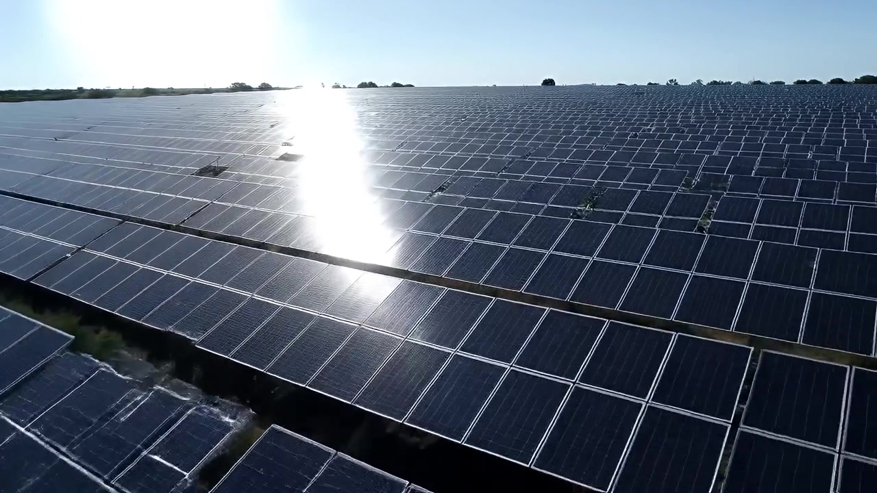 Veduta aerea di un grande impianto fotovoltaico in un campo soleggiato.