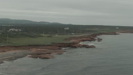 aerial flight along magdalen islands coastline with green plains and buildings