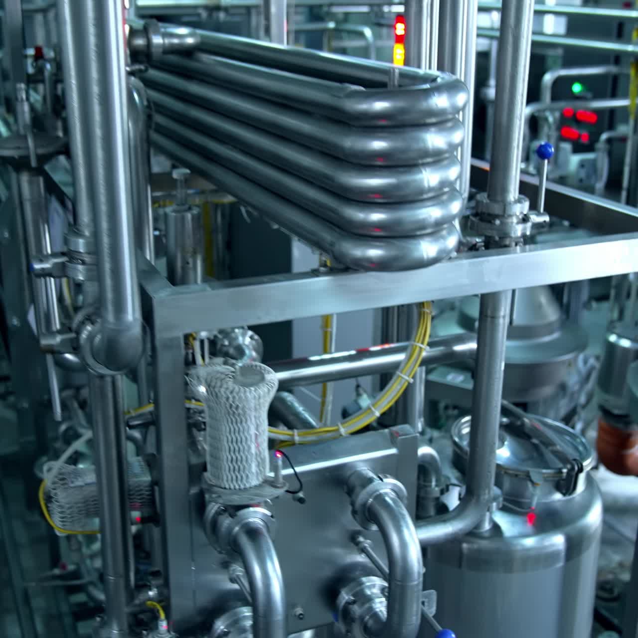 Milk and water pipelines at a modern dairy factory. Tanks, pipes and faucets close up. Gradual lifting above the factory equipment