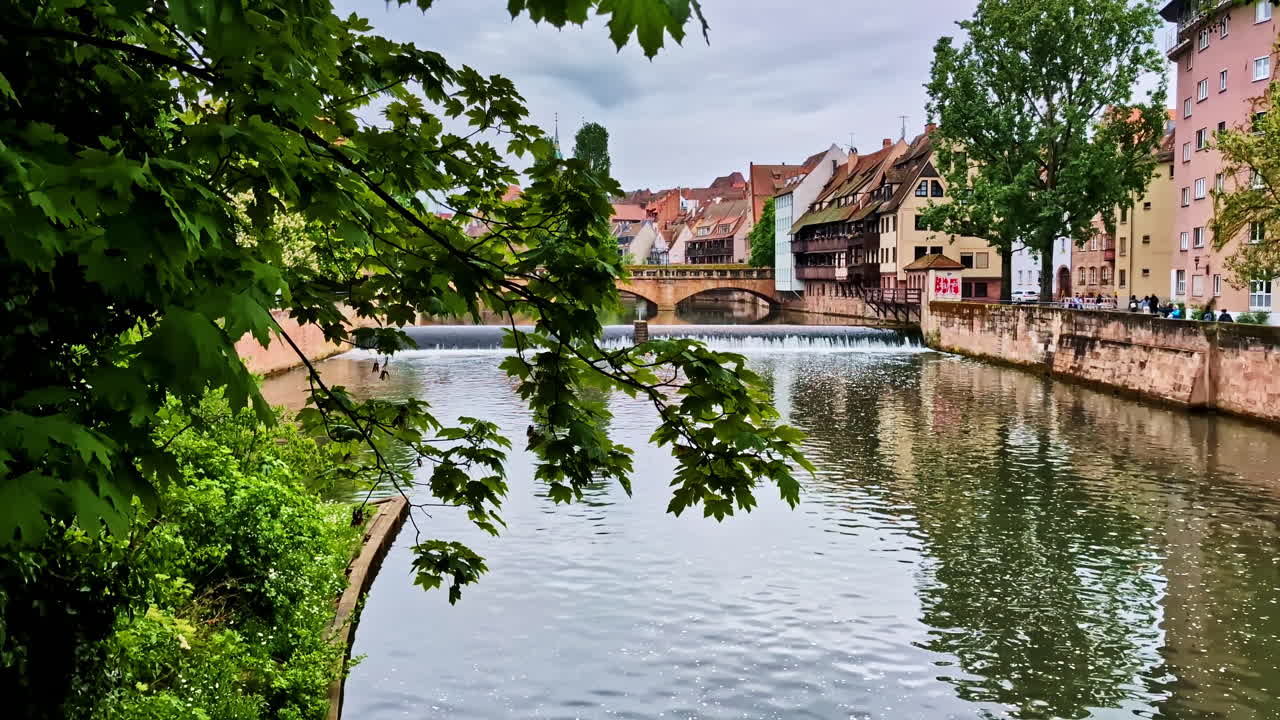 View of Maxbrücke bridge and Pegnitzwehr weir on Pegnitz River in Nurnberg, Germany through leaf frame