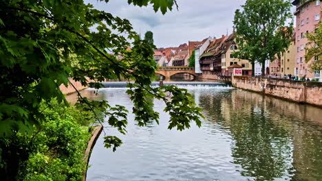 view of maxbrücke bridge and pegnitzwehr weir on pegnitz river in nurnberg, germany through leaf frame