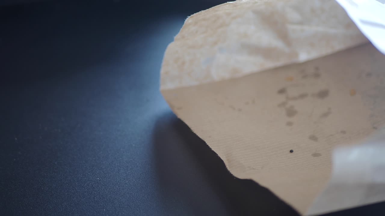 한 손이 종이 봉투에 손을 고 신선한 크로아산을 꺼낸다.