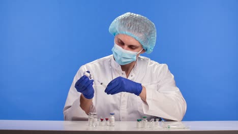de la creación de una vacuna contra el coronavirus. un médico que lleva guantes de protección, una máscara y un traje está llenando una jeringa con una vacina contra el covid-19. pantalla azul clave de croma. cerrar. cámara lenta