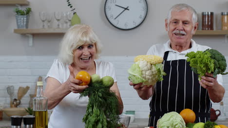 una pareja de abuelos mayores en la cocina. un hombre y una mujer maduros recomiendan comer alimentos vegetales crudos.