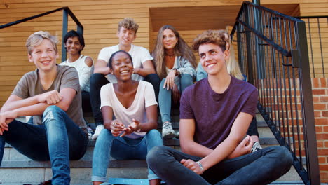 group of teenage students sitting on steps of college building