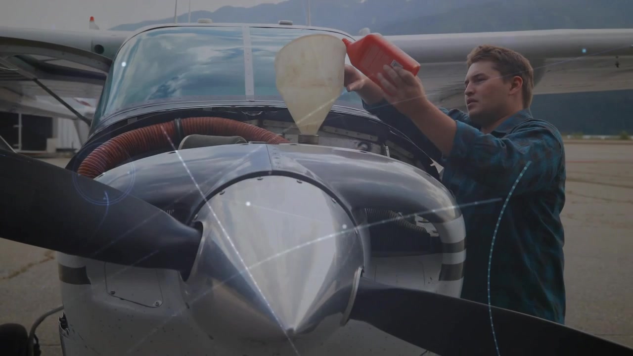Un tecnico avvia la manutenzione di un aeromobile versando prima del fluido e poi dell'olio in un imbuto, prima di ispezionare il motore.
