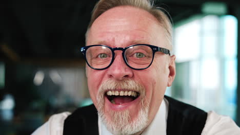 happy resilient face of a caucasian male with fair hair and beard wearing glasses. man smiling to camera widely close up.