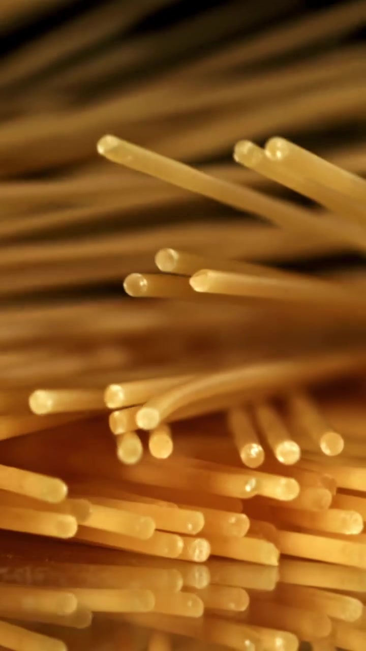 Spaghetti dorati che cadono al rallentatore su sfondo nero