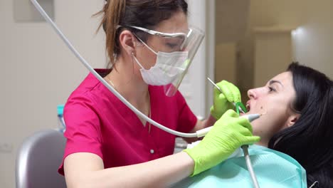 woman at the dental hygienist getting professional tooth whitening and ultrasound cleaning. dentist using saliva ejector or dental pump to evacuate saliva. shot in 4k