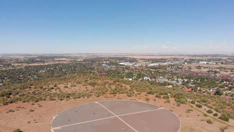 DRONE-Reveal-Shot-of-Water-Supply-Tank-supplying-water-to-a-Town-in-the-Background-on-a-Sunny-Day