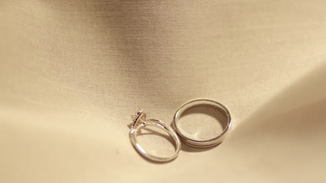 dropping a pair of engagement rings on a soft cottony cloth as it bounces and slowly settles in the middles of the fabric