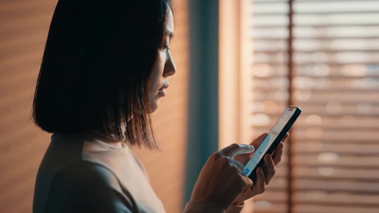 A Contemplative Woman Engaged with Her Smartphone in a Warmly Lit Room, Highlighting Focus and Modern Communication in Everyday Life