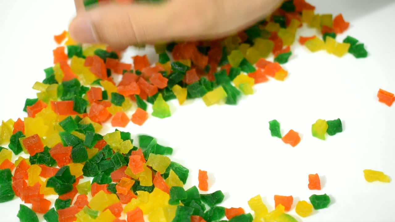 un primer plano de una mano recogiendo caramelos de frutas