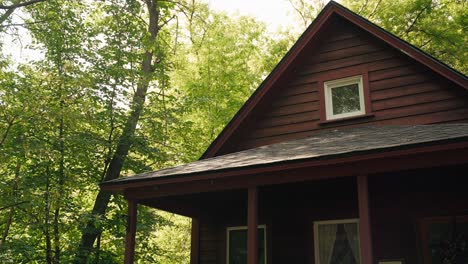 Looking-up-at-a-maroon-cabin-in-the-middle-of-the-woods-with-the-sun-peaking-through-the-trees