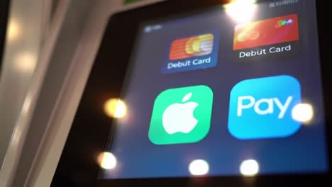 close-up of a payment terminal displaying digital wallet options featuring apple pay and debit card options in a modern transaction environment