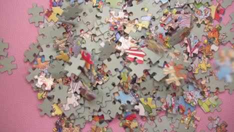 many puzzle pieces falling down on pink background - overhead view