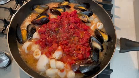 Seafood-simmering-in-a-pan-with-diced-tomatoes-and-herbs