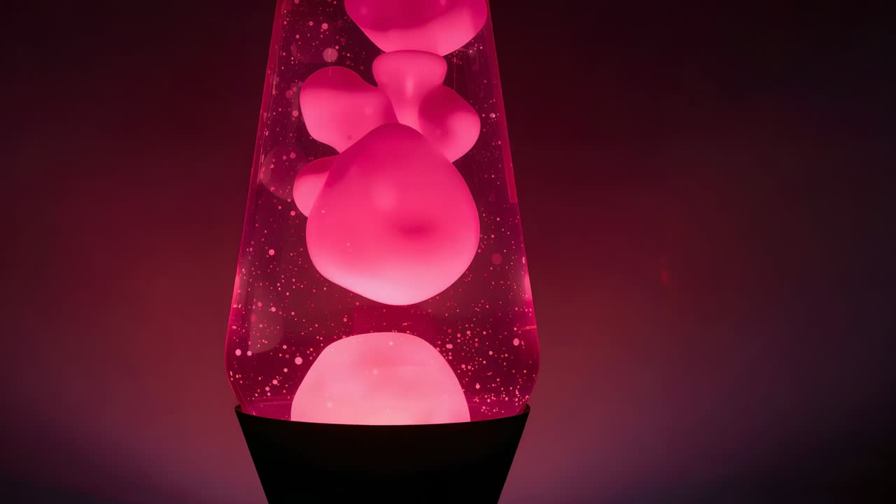Heating black base sending wax blobs rising merging sinking inside conical glass vessel with specks