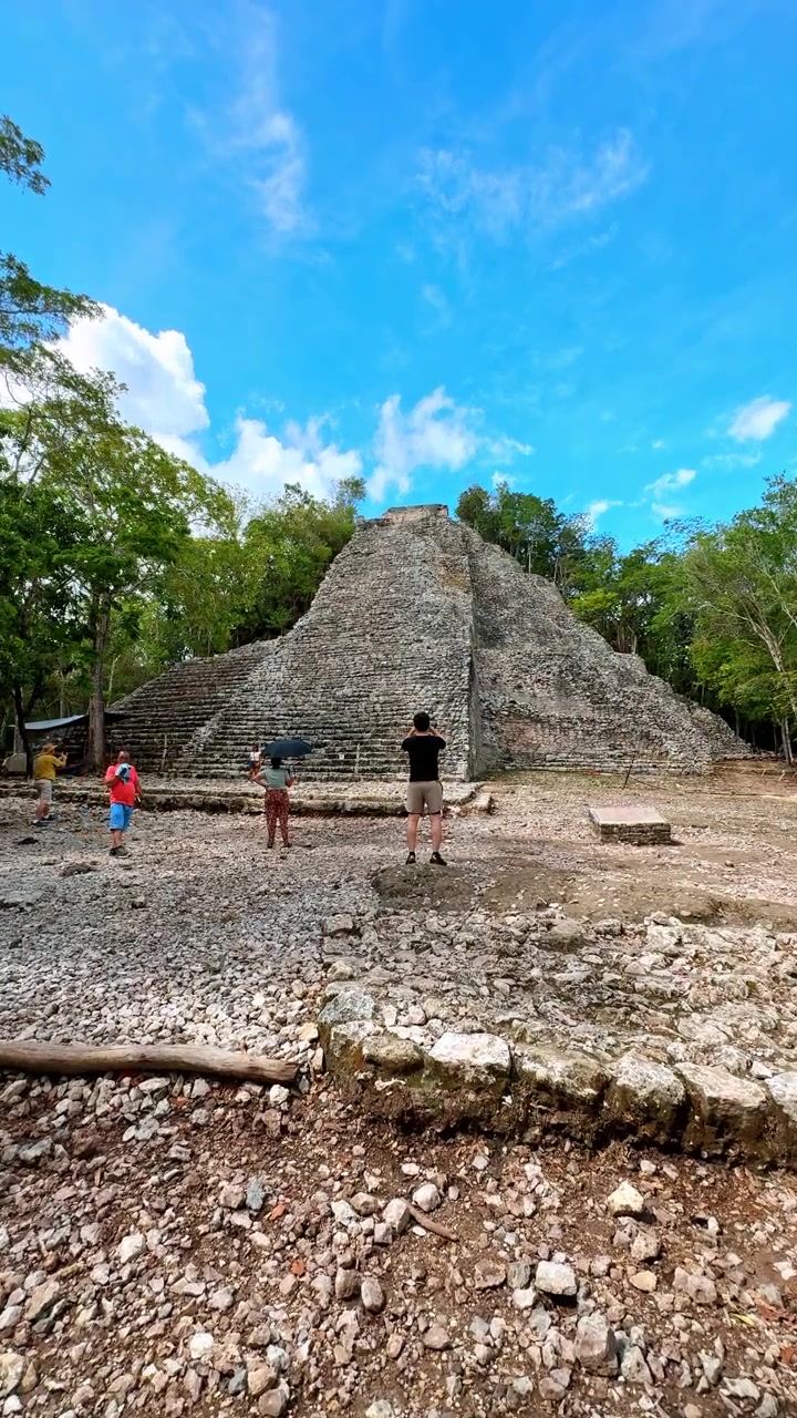 Tulum, Messico, 1 agosto 2025: Antiche rovine di piramidi di pietra Maya nella giungla tropicale messicana. Grande piramide a gradoni di pietra nel sito archeologico di Cobá sotto un cielo blu con turisti alla base.