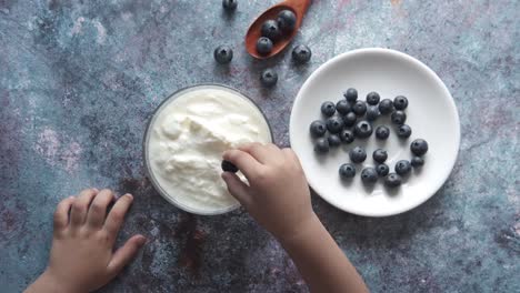 child eating yogurt with blueberries