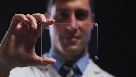 médico masculino caucásico mirando la interfaz digital de mano y sonriendo