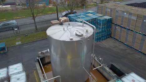 enorme contenedor en una fábrica de aceite industrial al lado de la carretera, vehículo de suministro que pasa - tiro estático de ángulo alto