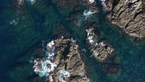 drone top down view of waves crushing on small rocky islands