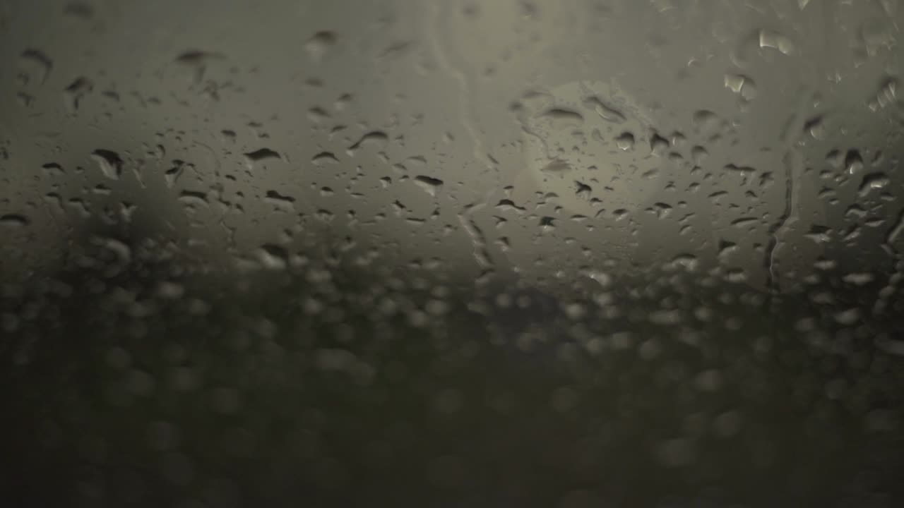 Close up of rainwater droplets on glass. Handheld