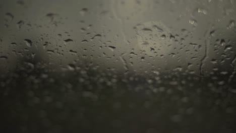 close up of rainwater droplets on glass. handheld