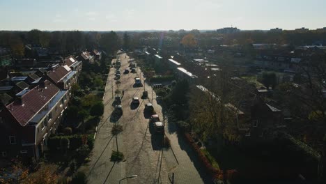 baja antena de coches que conducen por una calle tranquila en un tranquilo barrio suburbano en un soleado día de otoño
