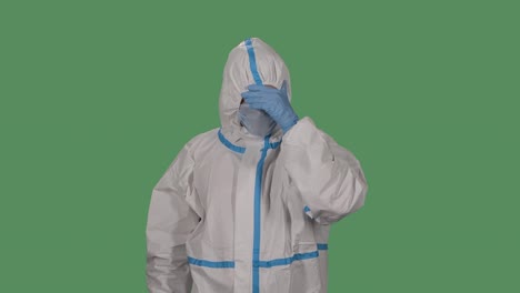 portrait of a man in a protective suit and medical mask looks at the camera holding his head with his hands showing that the head hurts. tired medic. green screen, chroma key. slow motion. close up