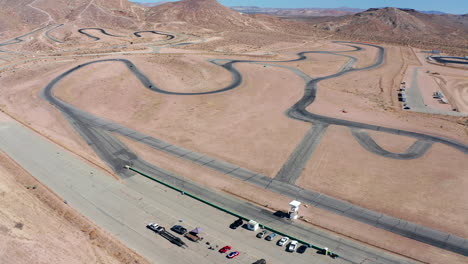 Los-Autos-Corren-Alrededor-De-Una-Pista-Gigante-En-El-Desierto-De-Mojave---Vista-Aérea-En-Cámara-Lenta