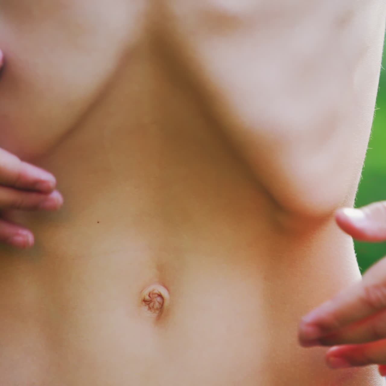 Close-up stomach of a boy. Young boy pulls his belly and shows ribs on his naked body.