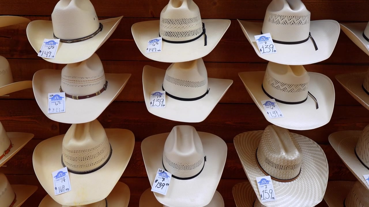 Chicago, USA, 21 maggio 2026: File di cappelli da cowboy di paglia con cartellini del prezzo su un espositore a parete in legno. Vista dall'alto di cappelli intrecciati bianchi e beige disposti a griglia.