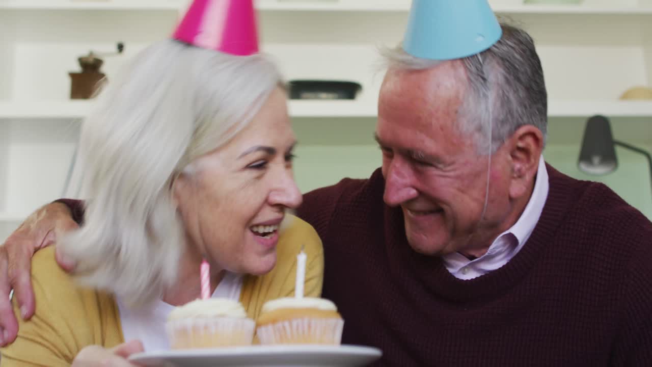 Ritratto di felice coppia anziana caucasica che festeggia un compleanno e effettua una videochiamata