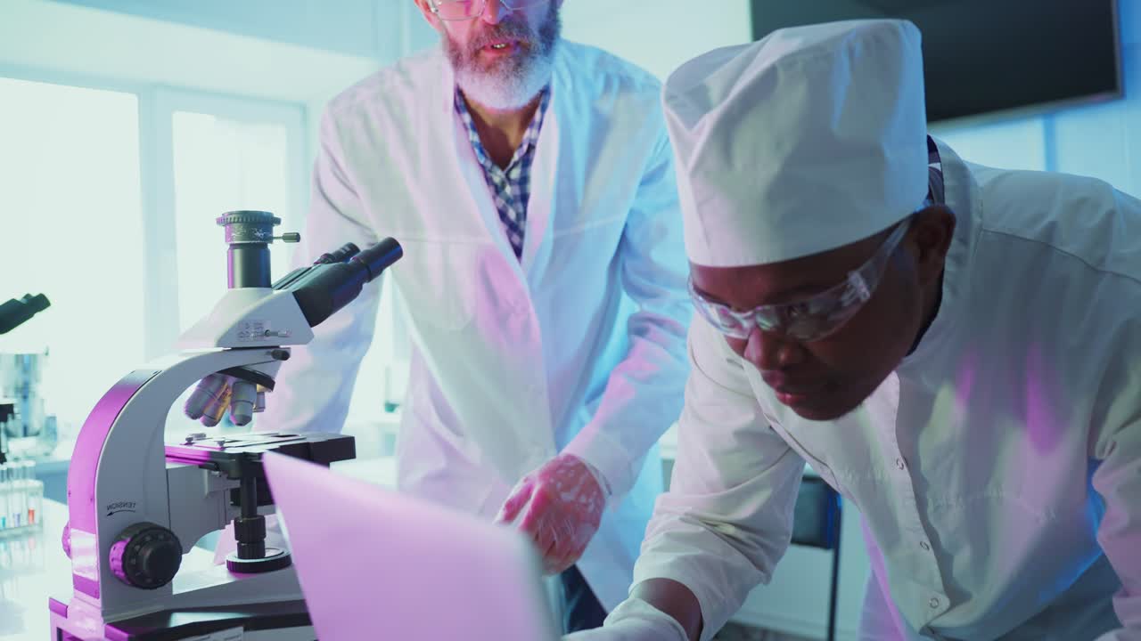Scientists Collaborating on Research with Microscope and Laptop in Laboratory