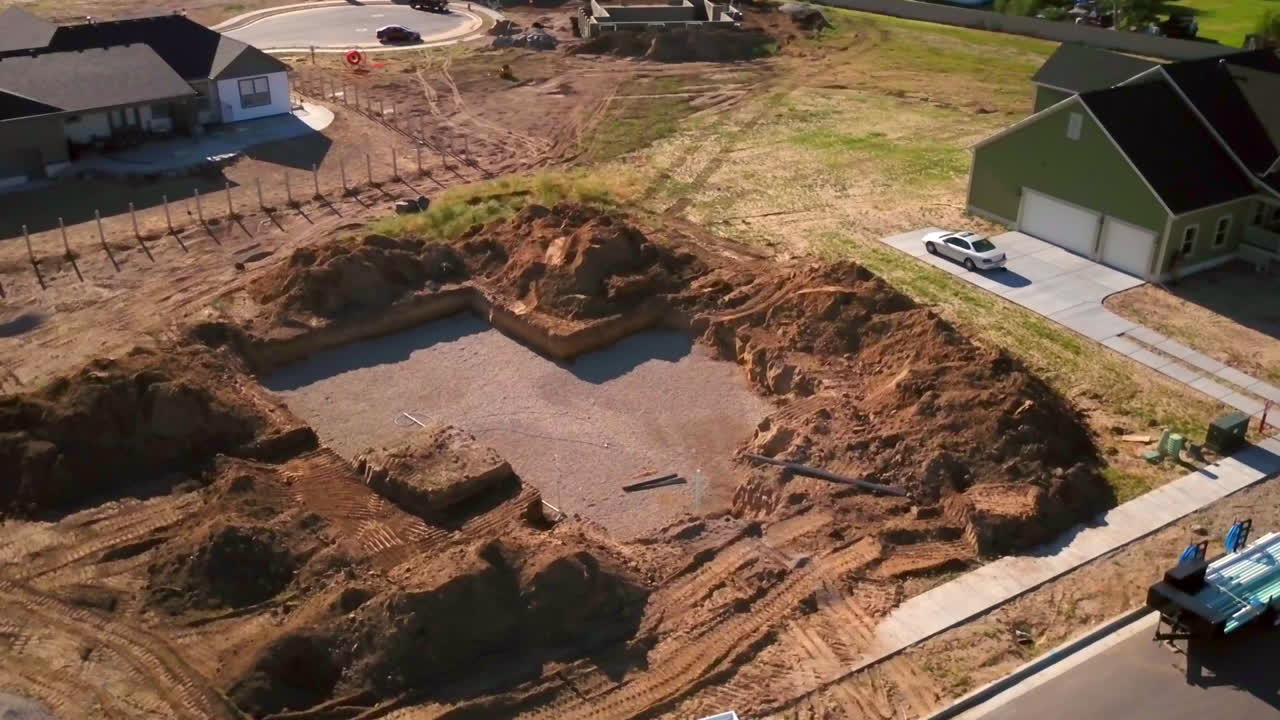 un tiro de drones girando alrededor de un agujero excavado recientemente para el comienzo de una nueva casa a punto de construir