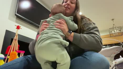 young woman babysitting, playing on the floor before picking baby up to comfort