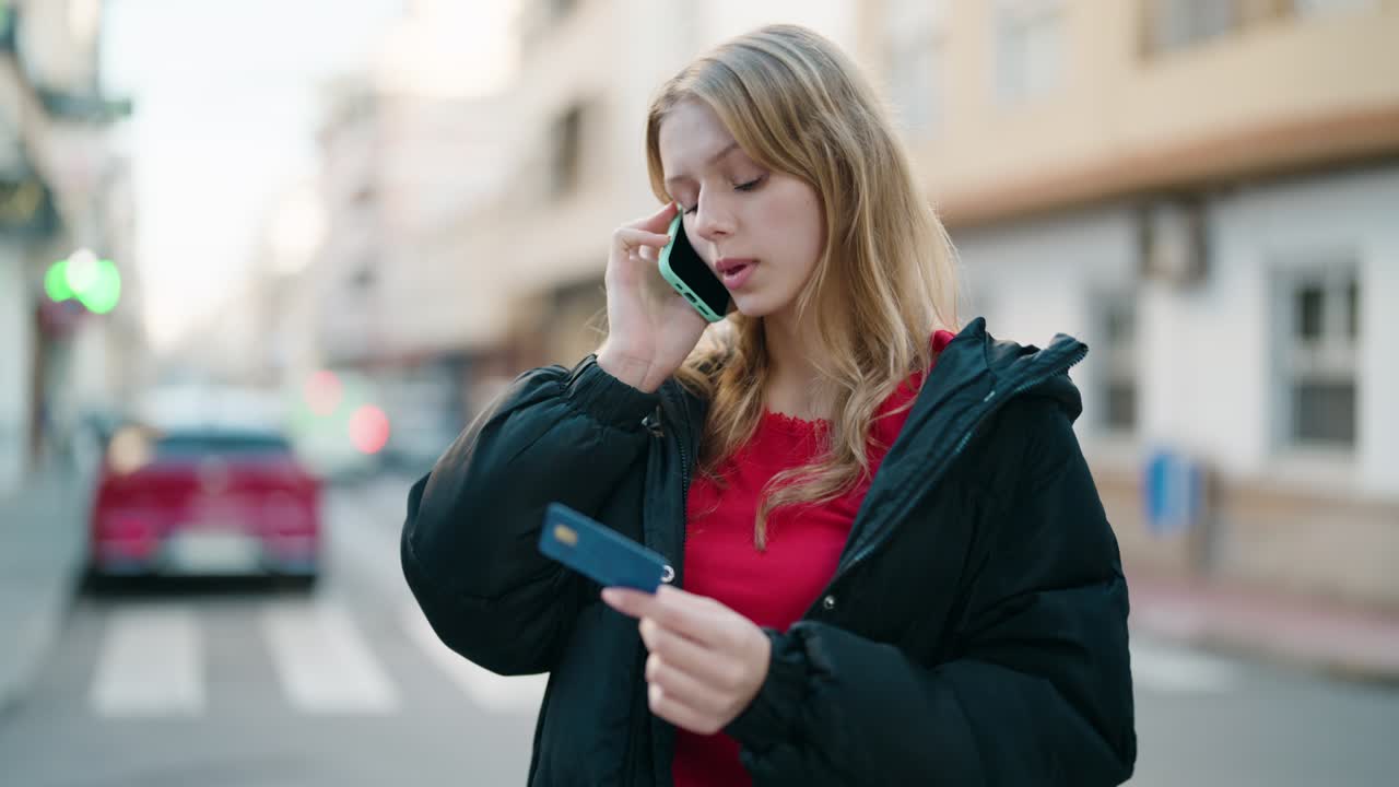 Jong blond meisje belt met de smartphone en gebruikt een creditcard op straat