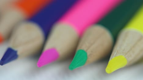 extreme close up of orange, blue, pink, green, and yellow colored pencils, isolated on white